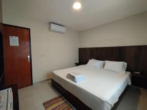 1 dormitorio con 1 cama blanca grande y cabecero de madera en Hotel Villa en San Juan del Paraná