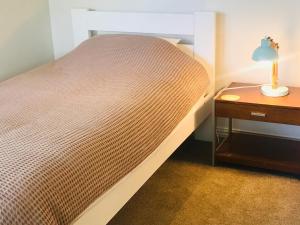 Cama en habitación pequeña con mesita de noche en Beach Lodge en Auckland