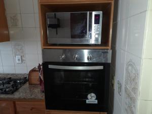 La cocina está equipada con microondas y horno. en Condominio Binacional, en Santana do Livramento