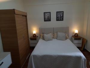 1 dormitorio con 1 cama blanca grande y 2 mesitas de noche en Condominio Binacional, en Santana do Livramento