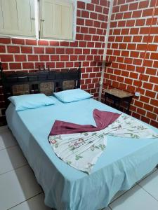 uma cama num quarto com uma parede de tijolos em Casa de Temporada das Mangueiras em Olinda