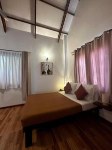 a bedroom with a large bed with pink curtains at Isola del Sole Villas and Resort in General Luna