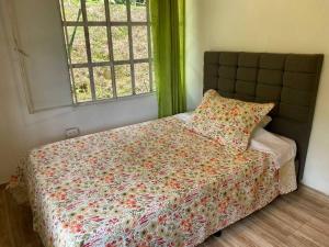 a bedroom with a bed with a floral comforter and a window at Casa Kakawa Ecolodge in Samaná