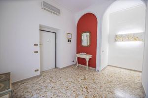 un pasillo con una pared roja, una mesa y un espejo en Green Rose Appartamento nel cuore di Roma, en Roma
