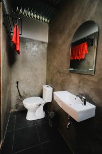 a bathroom with a white toilet and a sink at BAMBOO SHACK in Bukittinggi