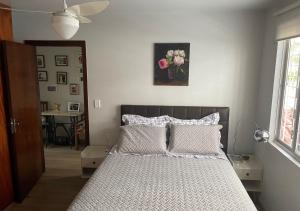 1 dormitorio con 1 cama con sábanas blancas y flores rosas en Casa ótima localização, en Curitiba