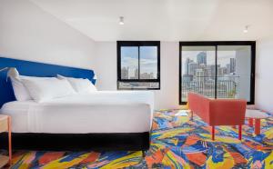 um quarto com uma cama branca e uma cadeira vermelha em Adge Hotel and Residences em Sydney