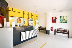 um lobby de loja com dois bancos e paredes amarelas e brancas em Golden Roof Hotel Sunway Ipoh em Ipoh