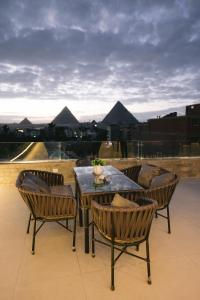 een patio met een tafel en stoelen op een dak bij Tuya Pyramids Inn hotel in Caïro