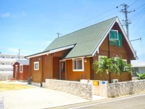 una casa marrone con una recinzione di fronte di 島ログ a Miyakojima