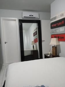 a bedroom with a white bed and a mirror at Flat Sandra in Teixeira de Freitas
