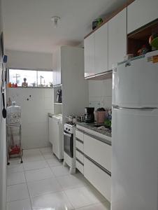 a kitchen with white cabinets and a white refrigerator at Flat Sandra in Teixeira de Freitas