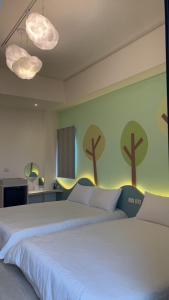 1 dormitorio con 2 camas y árboles pintados en la pared en Mi Hai B&B, en Magong