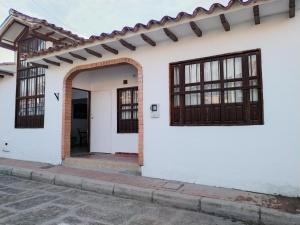 a white house with an archway and windows at HOSPEDAJE - SANDANED in Villa de Leyva