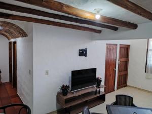 a living room with a flat screen tv and wooden beams at HOSPEDAJE - SANDANED in Villa de Leyva