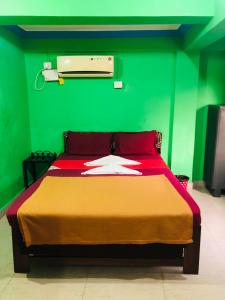 ein grünes Schlafzimmer mit einem Bett mit einer roten Tagesdecke in der Unterkunft Small Daddy Baga Beach in Baga