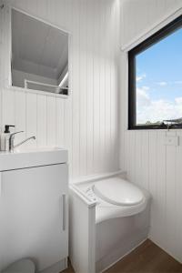 a bathroom with a toilet and a sink and a window at Tiny Charm in Lake Charm