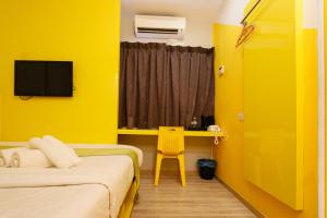 a yellow room with two beds and a desk at Golden Roof Hotel Sunway Ipoh in Ipoh