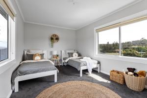 twee bedden in een witte kamer met twee ramen bij Legana Lodge - Your home away from home - Catering for up to 12 guests in Legana