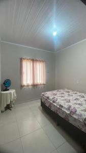 a bedroom with a bed and a window and a table at Casa Azul do Capão in Palmeiras