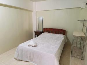 a bedroom with a bed with white sheets and shoes on it at RAYAS Guesthouse- No Credit Card Needed in Baguio