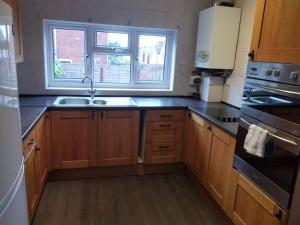 a kitchen with wooden cabinets and a sink and a window at Central Reading 4 Bedrooms 2Baths Free Parking in Reading