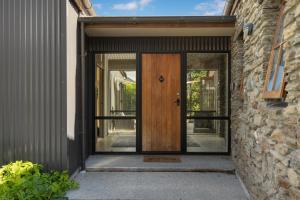 una puerta de madera en un edificio con una pared de piedra en Maytime Cottage - Arrowtown Holiday Home, en Arrowtown