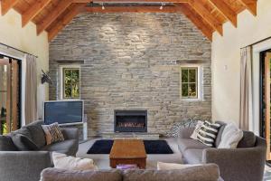 sala de estar con chimenea y pared de piedra en Maytime Cottage - Arrowtown Holiday Home, en Arrowtown