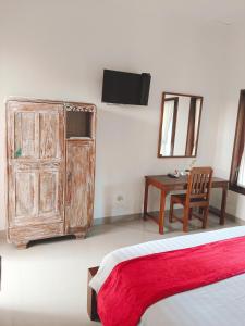 a bedroom with a bed and a wooden cabinet and a table at Taman Bali Homestay in Sanur