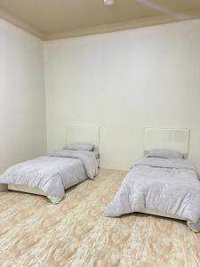 two beds in a room with white walls at شقة الشفاء فالي in Hail