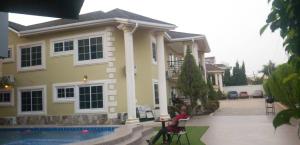 a woman sitting in a chair in front of a house at FOKUZZY LODGE in Accra