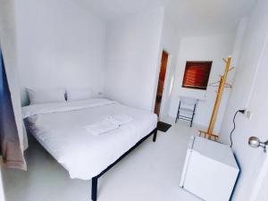 a white bedroom with a white bed and a chair at เบา ป่าตอง Bao Pathong Beach in Patong Beach