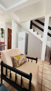 ein Wohnzimmer mit einem Stuhl und einem Kühlschrank in der Unterkunft Aconchegante sobrado próximo ao mar in Capão da Canoa