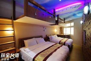 2 camas en una habitación de hotel con luces moradas en 自由塔精品民宿, en Magong