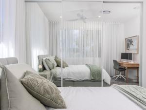 a white bedroom with two beds and a desk at Luxury Mermaid Waters Holiday Home in Gold Coast