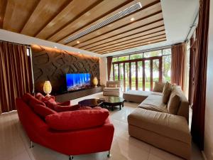 a living room with a red couch and a tv at Amatapura Beachfront Villa 10 , SHA Certified in Ao Nam Mao
