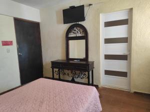 een slaapkamer met een bed, een dressoir en een spiegel bij Hotel Regional San Marcos in Tuxtla Gutiérrez