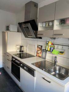 cocina con fregadero y fogones horno superior en Apartment Düsseldorf-Süd, en Düsseldorf