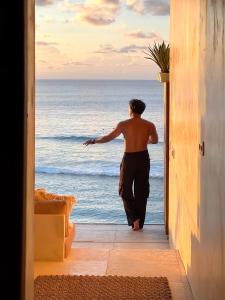 a man looking out at the ocean from a doorway at Mahi Mahi Beach Shack And Suites in Uluwatu