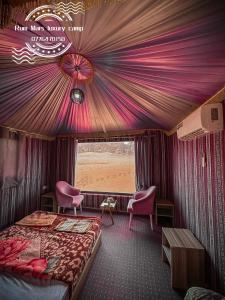 a bedroom with a bed and chairs in a train car at Rum Mars luxury camp in Wadi Rum