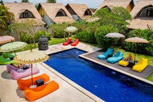 een zwembad met kleurrijke stoelen en parasols naast een zwembad bij United Colors of Bali in Canggu