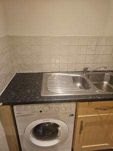 een keuken met een wasmachine en een wastafel bij Big double room with bathroom in 2 bedroom flat kitchen is shared in Harrow on the Hill