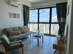 un soggiorno con divano e una grande finestra di Cozy Urban Suites Georgetown View a Jelutong
