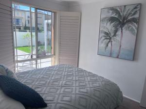 a bedroom with a bed and a picture of palm trees at Toowoon Bay - Private Pool - Outside Shower in Long Jetty