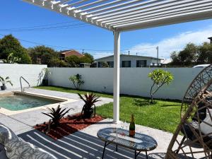 a patio with a table and chairs next to a pool at Toowoon Bay - Private Pool - Outside Shower in Long Jetty