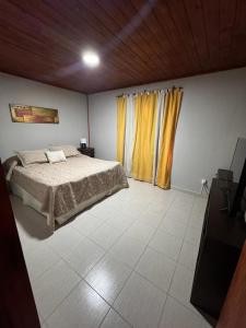 1 dormitorio con 1 cama y una ventana con cortinas amarillas en Cabaña cata en Villa Santa Cruz del Lago