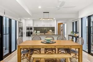 a kitchen and dining room with a wooden table and chairs at 'Bonnyview' Elegant 4-Bed Home By the Beach in Marcoola