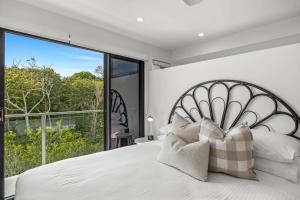 a bedroom with a white bed with a large window at 'Bonnyview' Elegant 4-Bed Home By the Beach in Marcoola