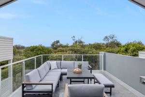 a patio with a couch and a table on a balcony at 'Bonnyview' Elegant 4-Bed Home By the Beach in Marcoola
