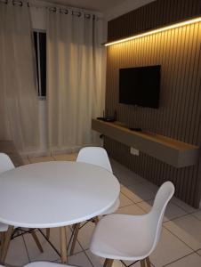 Cette chambre comprend une table et des chaises blanches ainsi qu'une télévision. dans l'établissement Aconchego da Barra, à Barra dos Coqueiros